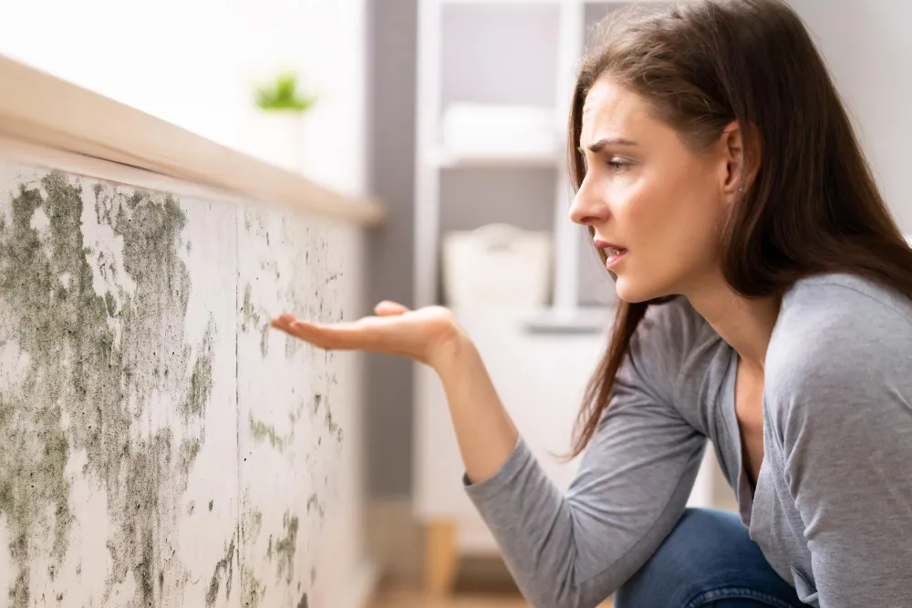 Mulher preocupada com mofo em apartamento alugado, questionando rescisão.